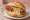 Knackwurst/Knockwurst: an illustration of pork, sausage, mustard and sauerkraut on kaiser roll.