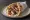 Kontosouvli se Pita (Κοντοσούβλι): an illustration of pork, tzatziki, tomato, onion and more on pita.
