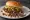 Loose Meat Sandwich: an illustration of beef, onion, mustard and pickle on burger bun.