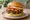 Lotteria — Kimchi Bulgogi Burger: an illustration of beef, egg, kimchi, lettuce and more on burger bun.