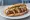 Loukaniko Thessalonikis: an illustration of pork and sausage on bread.