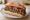 Loukaniko Trikala: an illustration of pork and sausage on bread.