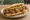Maxwell Street Polish: an illustration of sausage, onion and mustard on hot dog bun.