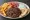 Merida Bifteki: an illustration of beef, onion, tomato and tzatziki on pita.