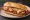 Milanesa a la Napolitana en Pan: an illustration of beef, ham, mozzarella and tomato on baguette.
