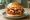 Mom's Touch — BBQ Bacon Burger: an illustration of chicken, bacon, cheddar cheese, bbq sauce and more on burger bun.
