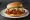 Mom's Touch — Fire Thigh Burger: an illustration of chicken and hot sauce on burger bun.