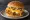 Mom's Touch — Triple Cheese Burger: an illustration of chicken, gruyère, cheddar cheese, cream cheese and more on burger bun.