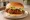 NeNe Chicken Sandwich: an illustration of chicken, lettuce, pickle and mayonnaise on burger bun.