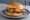 Oklahoma Onion Burger: an illustration of beef, onion, american cheese, pickle and more on burger bun.