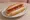 Pancho con Ketchup: an illustration of sausage and ketchup on hot dog bun.