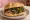 Panino con Salsiccia e Friarielli: an illustration of sausage, pork, garlic, pepper and more on kaiser roll.