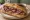 Pastrami Dip: an illustration of pastrami and au jus on hoagie roll.
