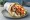 Pita Gyros Horis Kremydi: an illustration of pork, tomato, tzatziki and potato on pita.