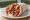 Pita Gyros me Ketchup: an illustration of pork, tomato, onion, tzatziki and more on pita.