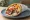 Pita Gyros/Souvlaki - Standard Fillings: an illustration of pork, tomato, onion, tzatziki and more on pita.
