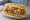 Po' Boy (Cochon de Lait): an illustration of pork, lettuce, tomato, pickle and more on baguette.