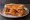 Raising Cane's Chicken Finger Sandwich: an illustration of chicken, burger sauce, lettuce, tomato and more on white bread.
