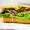 Close-up of a roast beef sandwich on a soft roll with avocado, lettuce, tomato and red onion, resting on deli paper.