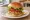Salmon Burger (Alaskan): an illustration of salmon, lettuce, tomato, dill and more on burger bun.
