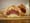 A halved sandwich wrapped in brown paper, showing piled corned beef, melted cheese and slaw on a toasted roll.