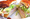 A halved turkey sandwich on Dutch crunch roll with shredded lettuce and red onion, resting on deli paper.