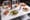 White patio table set with Dutch crunch sandwiches, a fried chicken sandwich, waffle fries, cutlet plates and drinks.