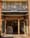 Souvla storefront with open wooden doors, blue letter-tile sign, three pendant lamps and stools inside