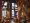 Dining room seen from above: tree-trunk columns wrapped in string lights, stained-glass windows, diners at wooden tables.