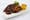 Glazed barbecue ribs topped with green onion on a white rectangular plate, with a square of cornbread and slaw.