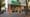 Corner storefront with a green FRATM Pizzeria Napoletana sign above a brick and wood-railed patio with green chairs.