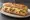 Sandwich à la Raclette: an illustration of gruyère, ham, potato, pickle and more on baguette.