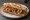 Sandwich Cassoulet: an illustration of pork, sausage, beans, onion and more on baguette.