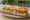 Sandwich Complet: an illustration of ham, cheese, lettuce, tomato and more on baguette.
