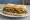 Sándwich de Bife: an illustration of beef, lettuce, tomato and mayonnaise on baguette.