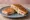 Sándwich de Jamón y Queso Caliente: an illustration of ham, cheese and butter on white bread.