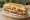 Sándwich de Lomo: an illustration of lettuce, tomato, cheese, mayonnaise and more on baguette.