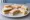 Sándwich de Miga Surtido: an illustration of ham, cheese, tomato, lettuce and more on white bread.