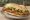 Sándwich de Milanesa: an illustration of beef, egg, lettuce, tomato and more on baguette.