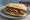 Sándwich de Ojo de Bife: an illustration of beef, chimichurri, lettuce and tomato on baguette.