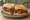 Sándwich de Pastrón: an illustration of pastrami, mustard and pickle on baguette.