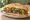 Sándwich Patagónico: an illustration of lamb, onion, tomato, lettuce and more on baguette.