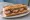 Sandwich Saucisse de Morteau: an illustration of butter, mustard and pickle on baguette.