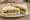 Sándwich Vegetariano: an illustration of lettuce, tomato, cucumber, cheese and more on white bread.