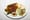 Oval white plate with two beef kofta kebabs, chicken kebab, yellow rice, hummus with red sauce, salad and pita wedges.