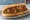 Sausage and Peppers Hero: an illustration of sausage, bell pepper, onion, olive oil and more on hoagie roll.