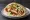 Schnitzel b'Pita (שניצל בפיתה): an illustration of chicken, hummus, tahini, tomato and more on pita.
