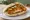 Schnitzel Cornflakes (שניצל קורנפלקס): an illustration of chicken, olive oil, hummus and tahini on pita.