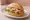 Seelachsbrötchen: an illustration of fish, onion, lemon, remoulade and more on kaiser roll.