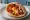 Shakshuka b'Pita (שקשוקה בפיתה): an illustration of egg, tomato, onion, bell pepper and more on pita.